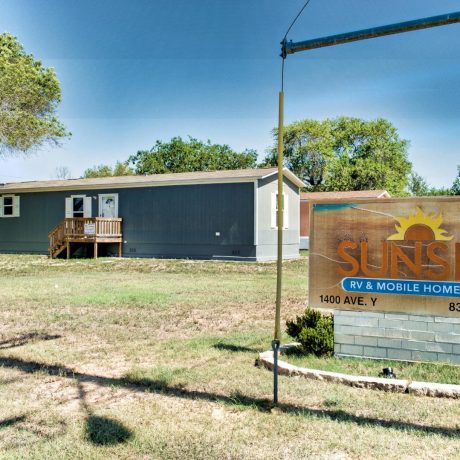 A colorful welcome sign located at the entrance of Sunset Mobile Home Park in Hondo, TX.